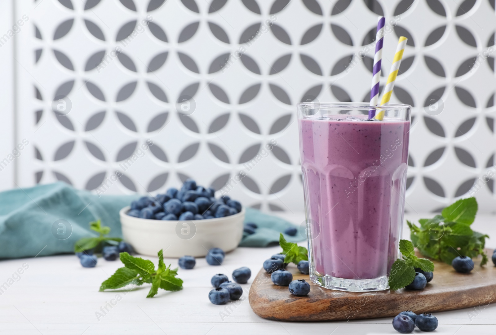 Photo of Glass of blueberry smoothie with mint and fresh berries on white wooden table, space for text
