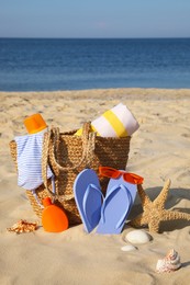 Photo of Bag and beach accessories on sand near sea
