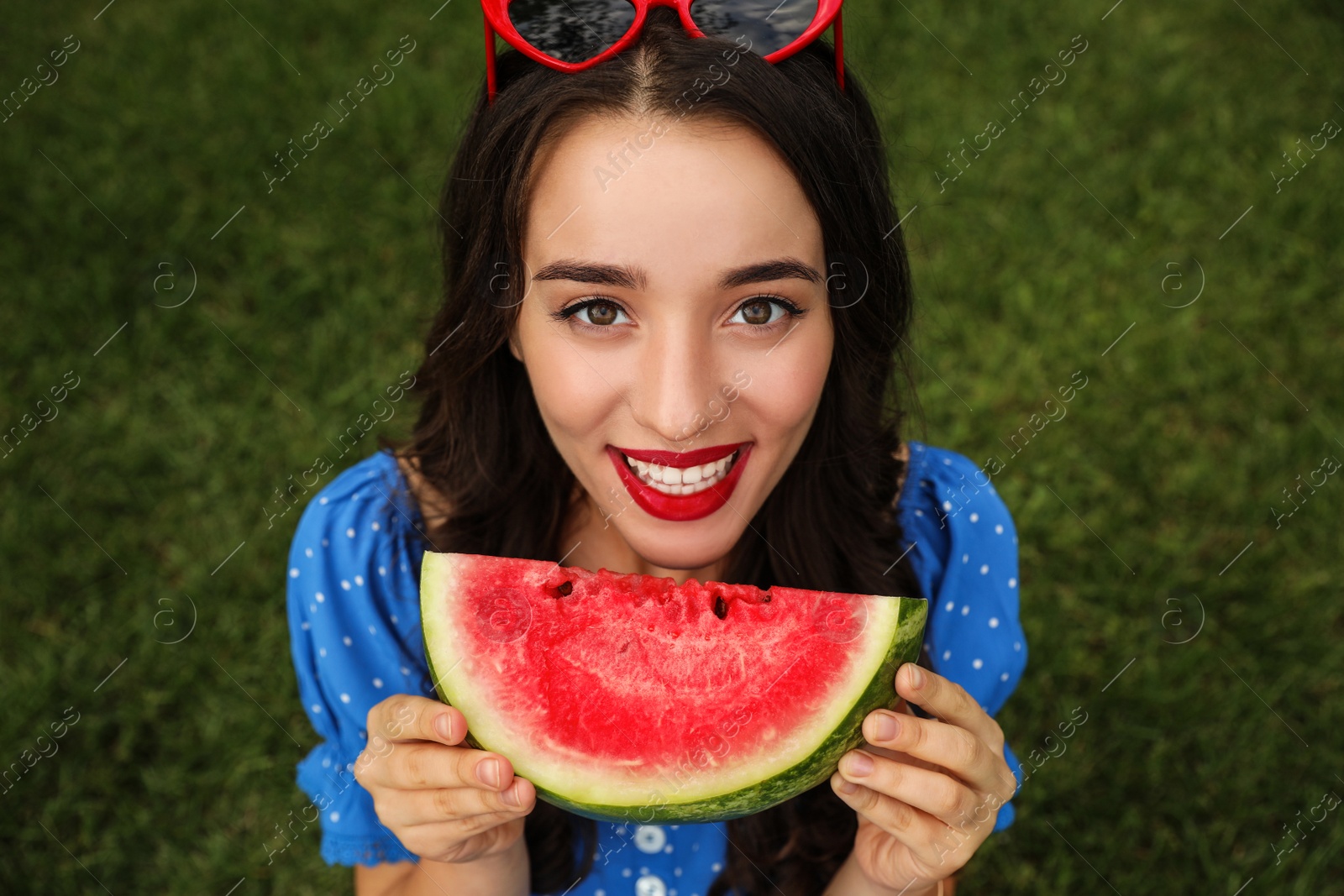 Photo of Beautiful young woman with watermelon on green grass outdoors