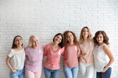 Group of women with silk ribbons near brick wall. Breast cancer awareness concept