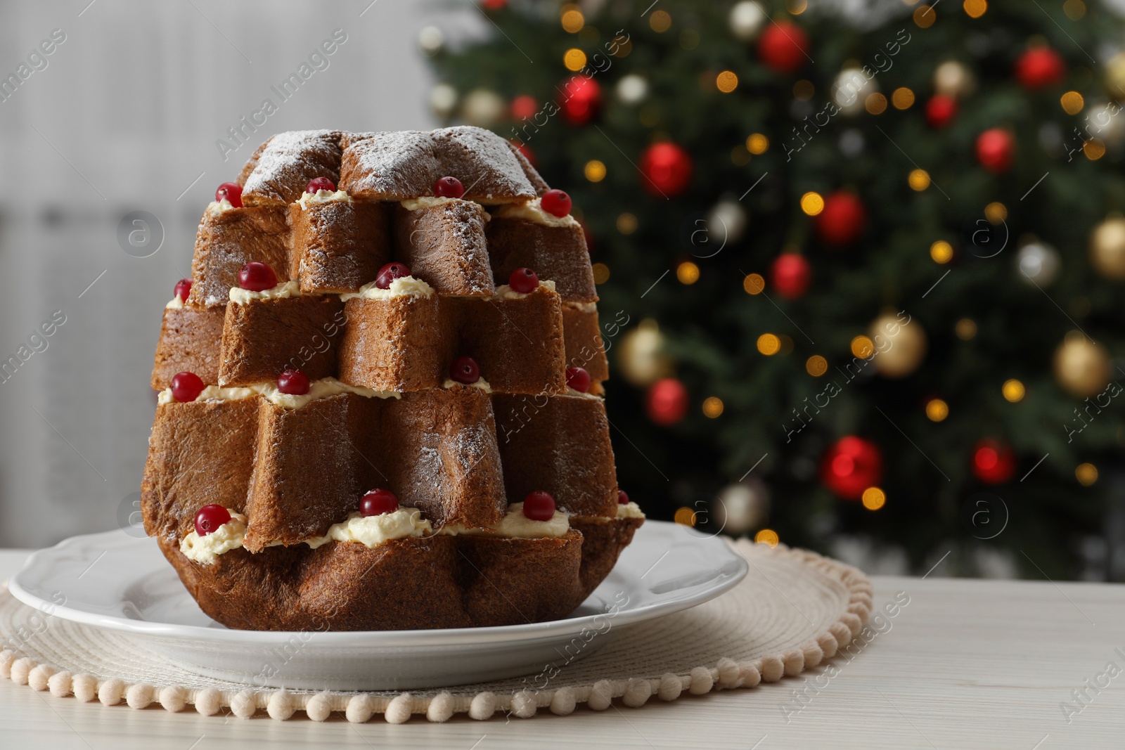 Photo of Delicious Pandoro Christmas tree cake with powdered sugar and berries on white table indoors. Space for text