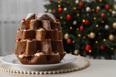 Photo of Delicious Pandoro Christmas tree cake with powdered sugar and berries on white table indoors. Space for text