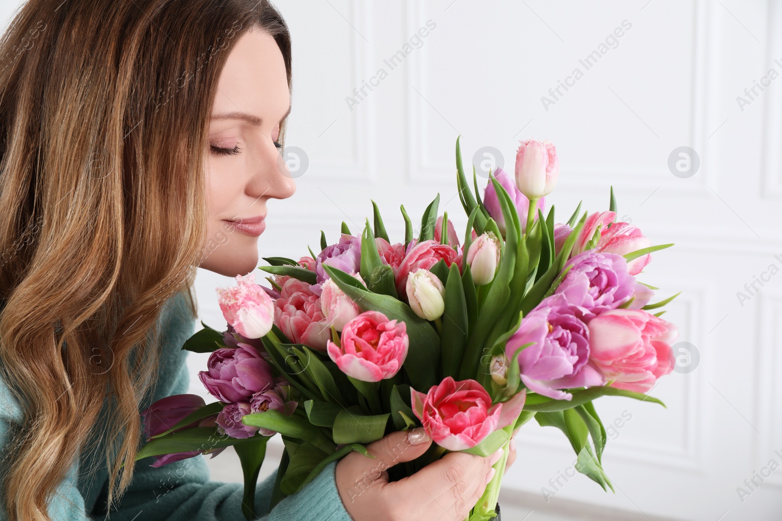 Photo of Young woman with bouquet of beautiful tulips indoors