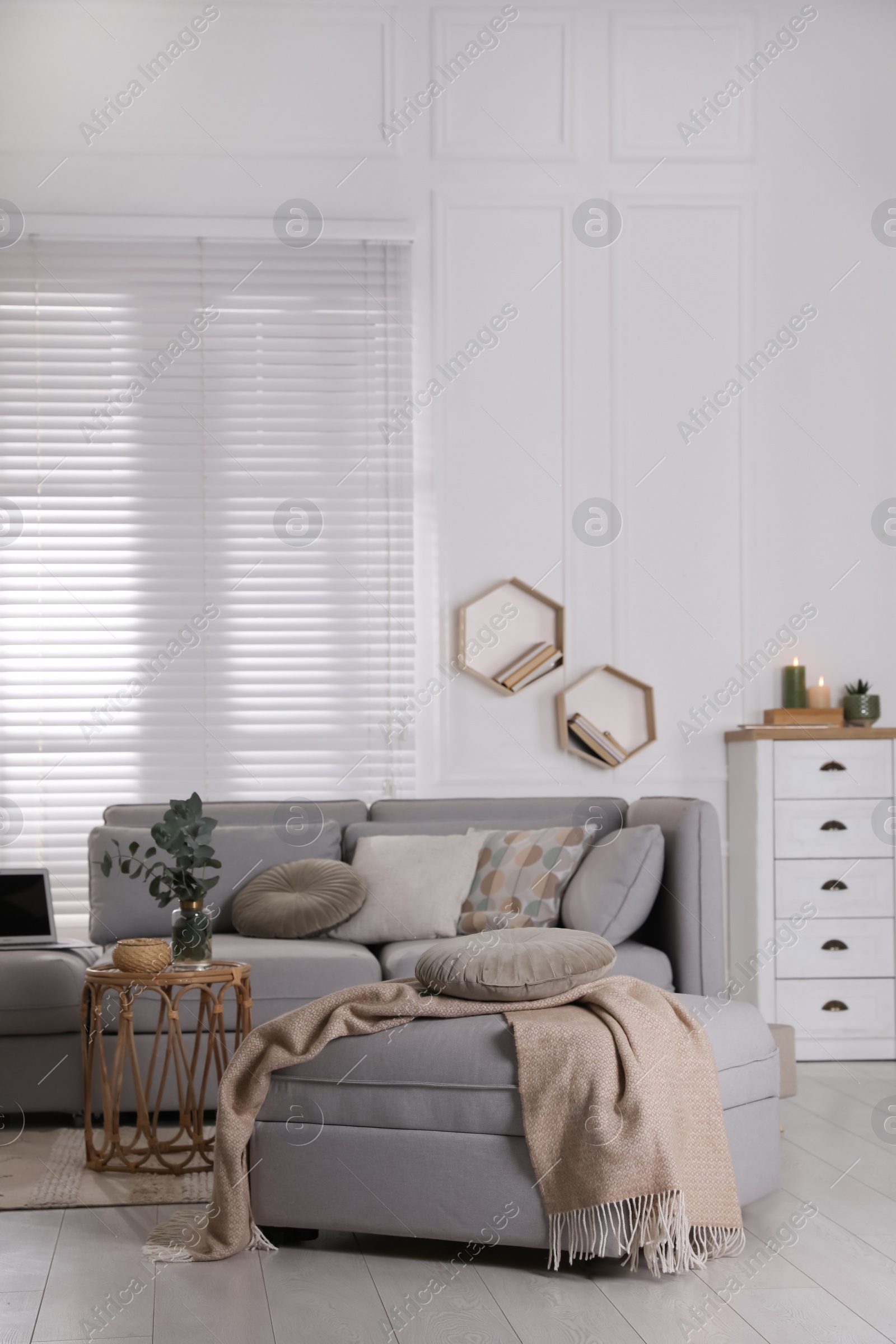 Photo of Living room with comfortable grey sofa, ottoman and stylish interior elements near window