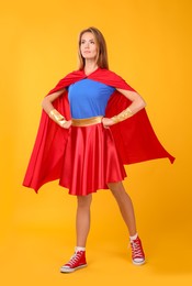 Photo of Confident woman wearing superhero costume on yellow background