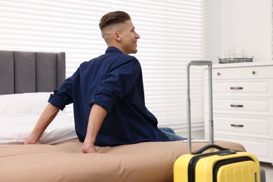 Photo of Smiling guest relaxing on bed in stylish hotel room