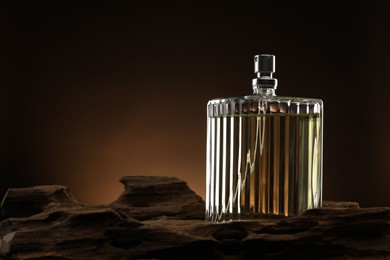 Luxury men`s perfume in bottle against brown background, space for text