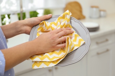 Photo of Woman wiping plate with towel in kitchen, closeup