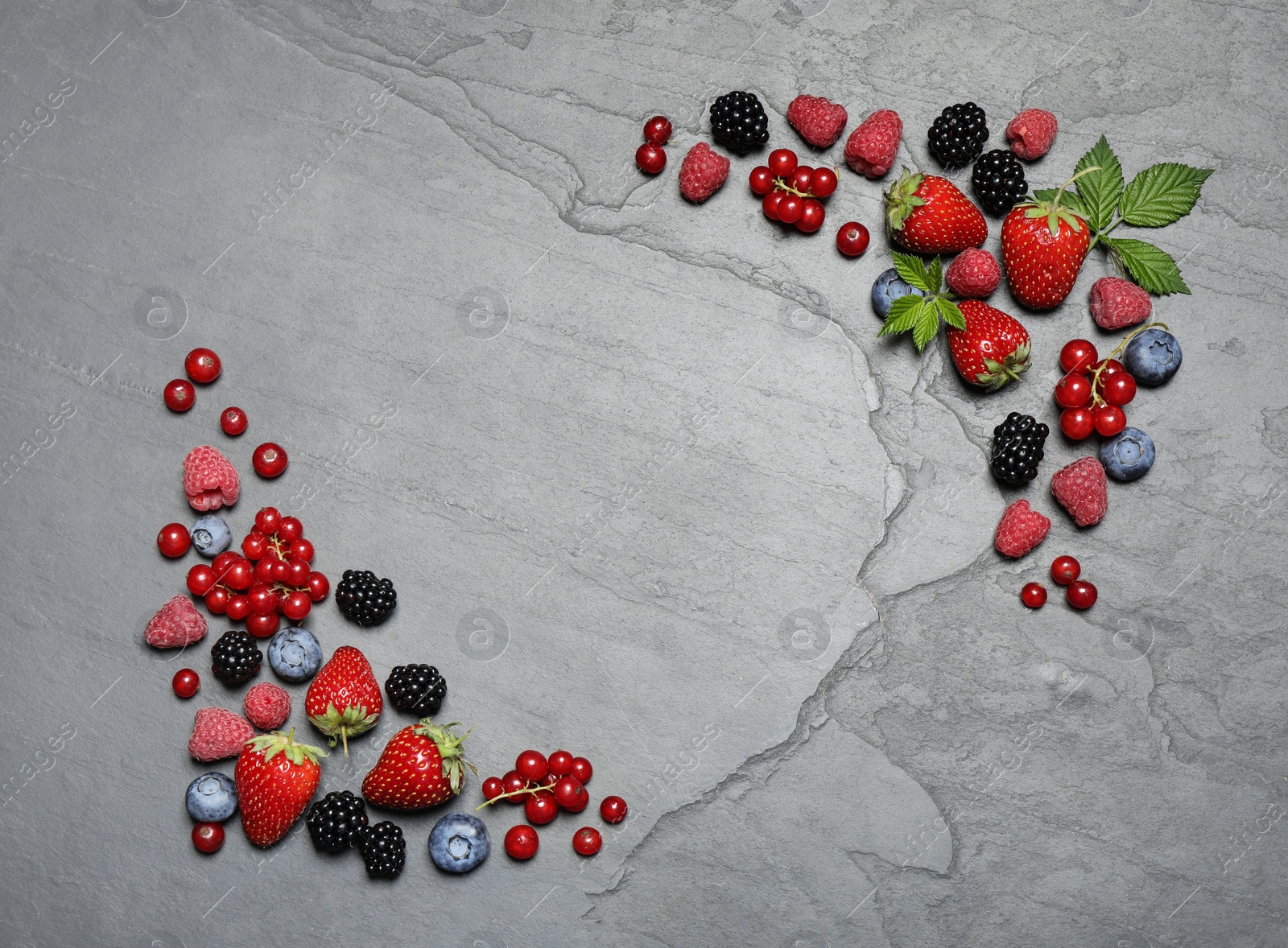 Photo of Different fresh berries on grey background, flat lay. Space for text