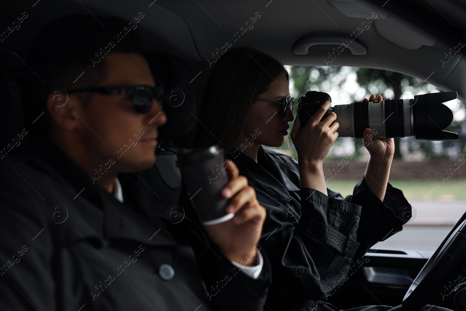 Photo of Private detectives with modern camera spying from car