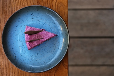 Photo of Plate with slice of berry cheesecake on wooden table, top view. Space for text