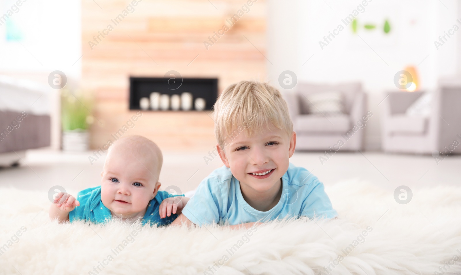 Photo of Cute boy with his little sister lying on fur rug at home