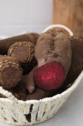 Whole and cut red beets in basket on table, closeup