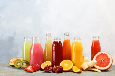 Bottles with tasty juices and ingredients on table