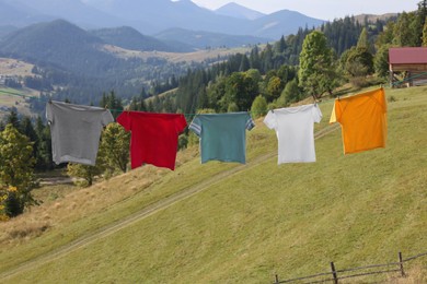 Photo of Washing line with clean laundry and clothespins in mountains