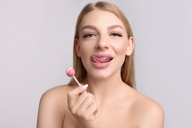 Photo of Beautiful young woman with lips covered in sugar eating lollipop on light grey background