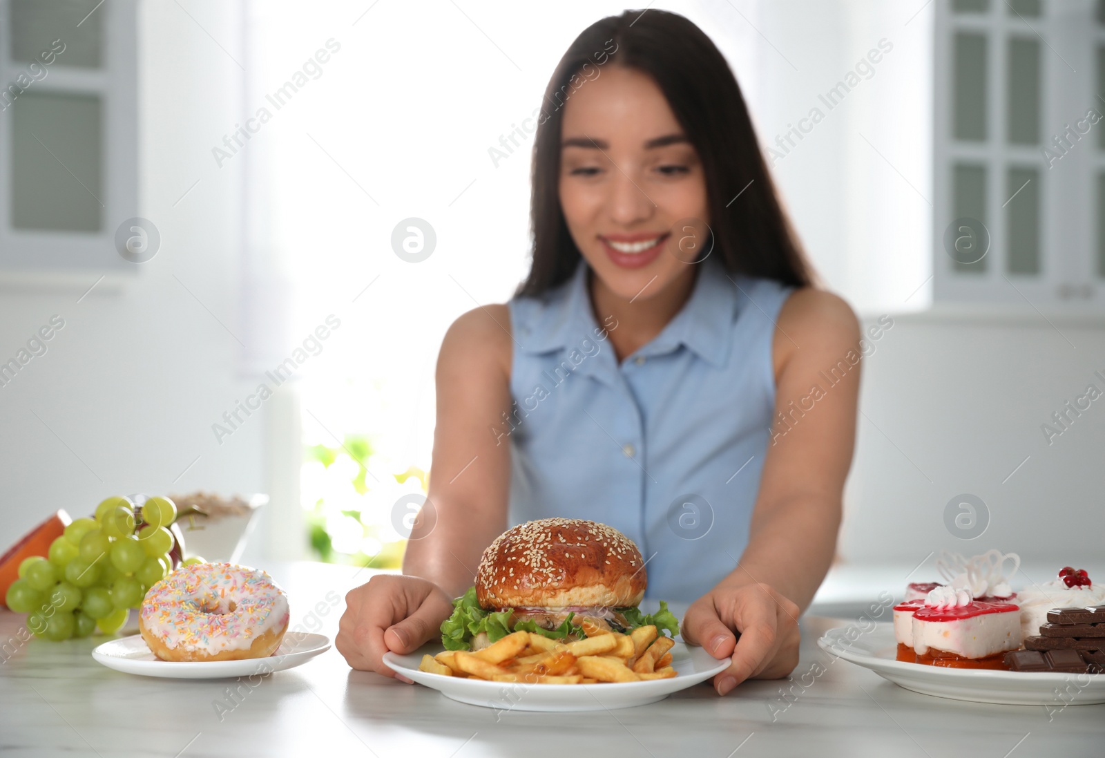 Photo of Concept of choice. Woman taking plate with tasty burger and French fries in kitchen, focus on food