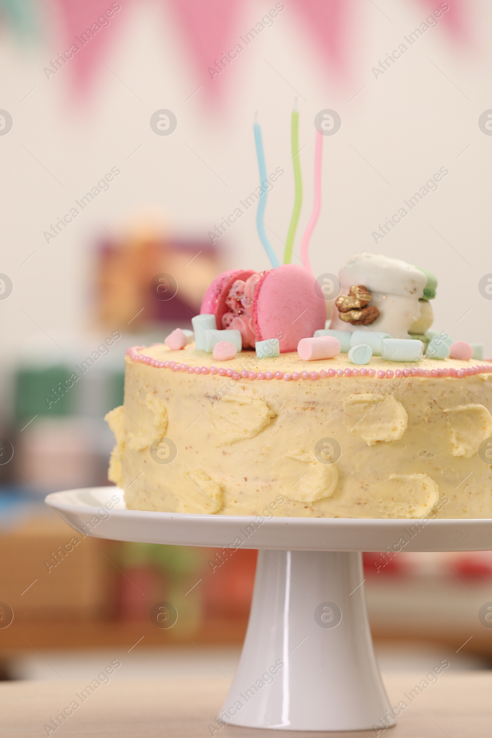 Photo of Delicious cake decorated with macarons and marshmallows on table against blurred background