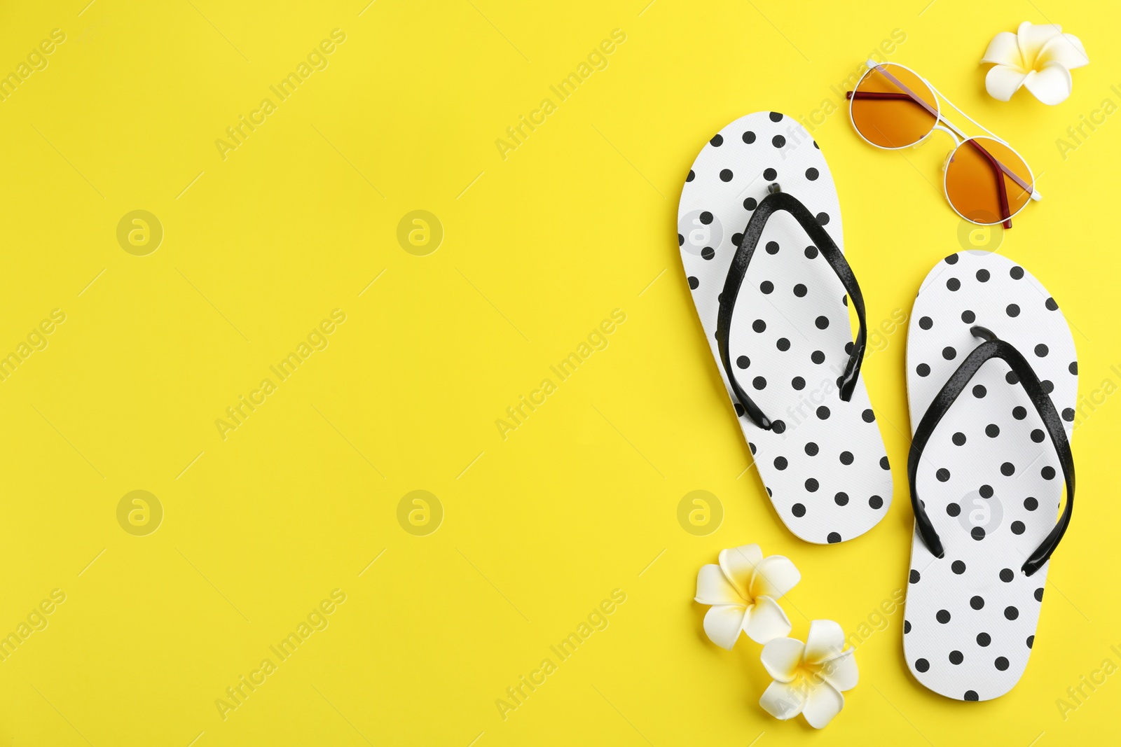 Photo of Flat lay composition with flip flops on yellow background. Space for text