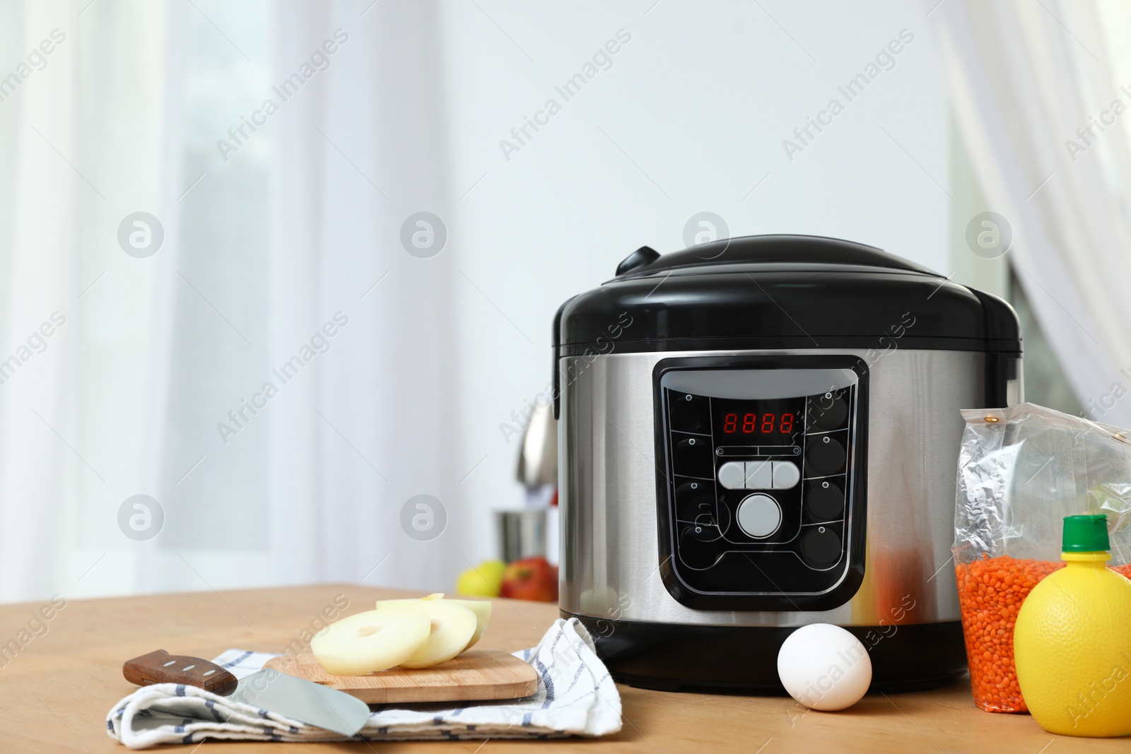 Photo of New modern multi cooker and products on table in kitchen. Space for text