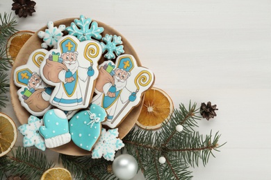 Photo of Tasty gingerbread cookies and festive decor on white table, flat lay. St. Nicholas Day celebration