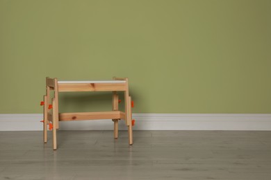 Photo of Stylish wooden stool near light green wall indoors. Space for text