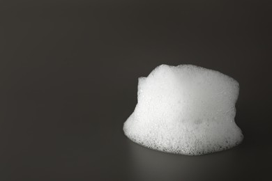 Photo of Drop of fluffy bath foam on grey background. Space for text