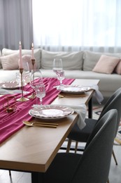 Photo of Beautiful table setting with burning candles and pink accent in dining room