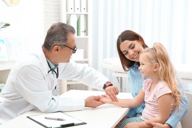 Young woman with daughter visiting doctor in hospital. Checking pulse