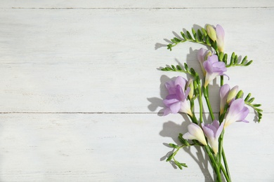 Photo of Beautiful fresh freesia flowers on wooden background, top view. Space for text