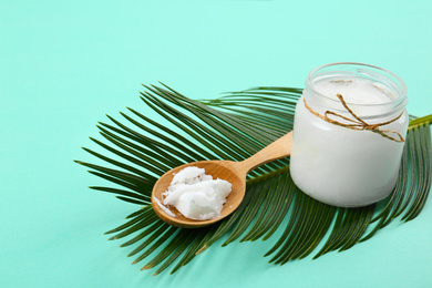 Organic coconut oil and palm branch on turquoise background. Healthy cooking