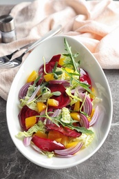 Photo of Bowl with tasty beets salad on gray table