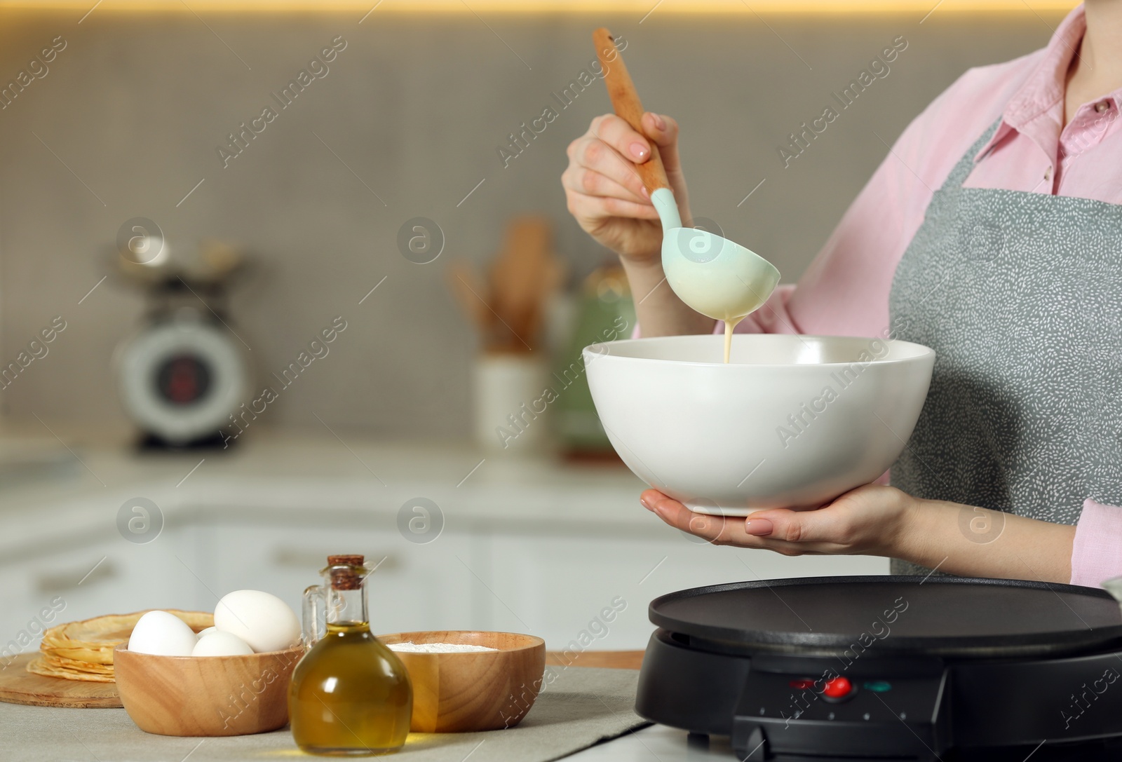 Photo of Woman with dough for crepes at table in kitchen, closeup