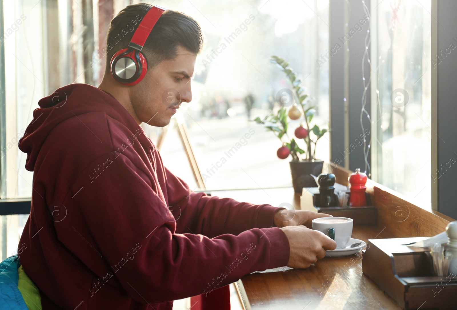 Photo of Man listening to audiobook at table in cafe