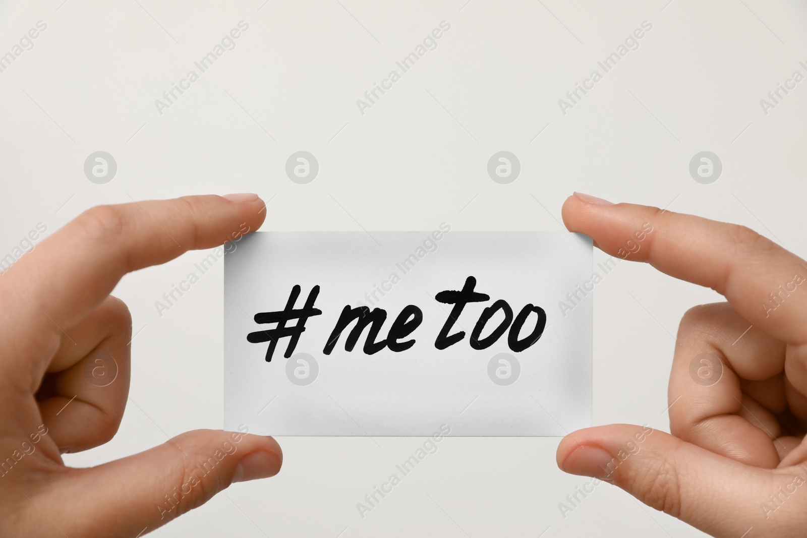 Photo of Woman holding paper with text MeToo against light background, closeup. Stop sexual assault