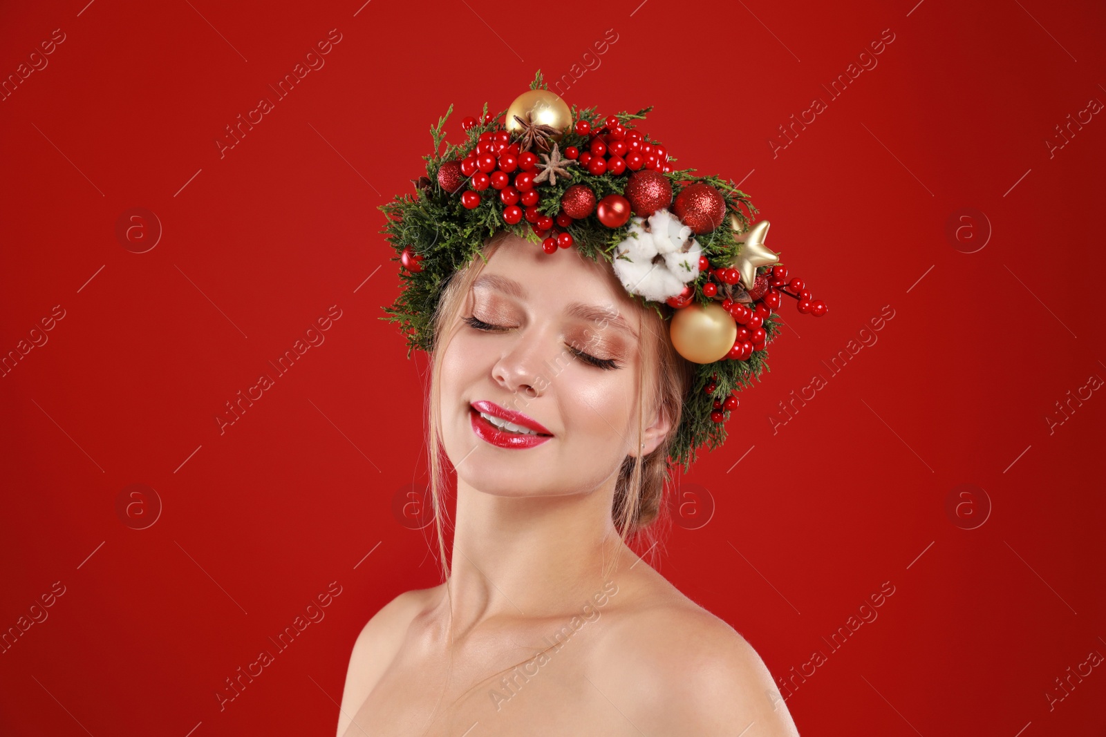 Photo of Beautiful young woman wearing Christmas wreath on red background