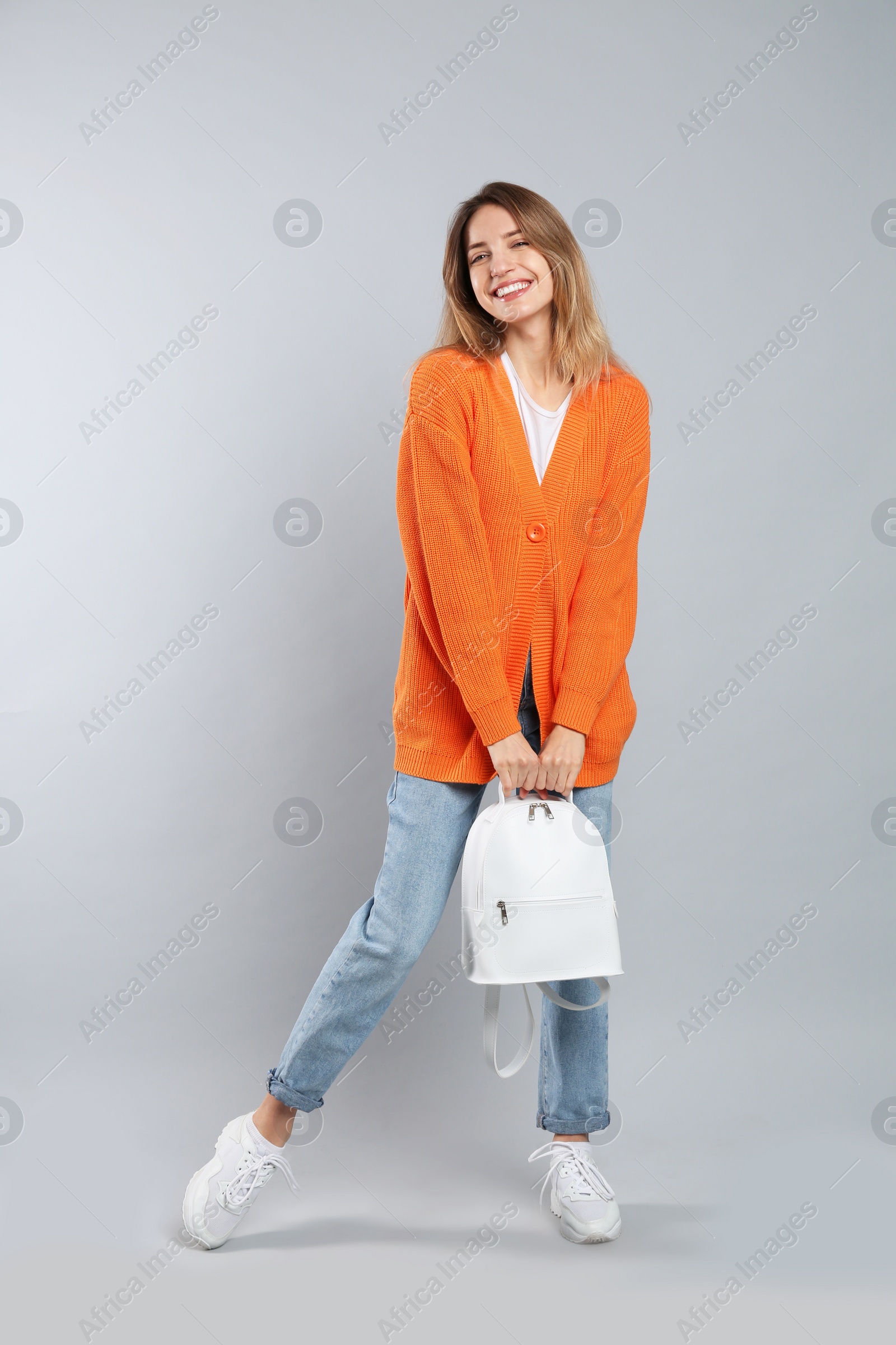 Photo of Happy woman with backpack on light grey background