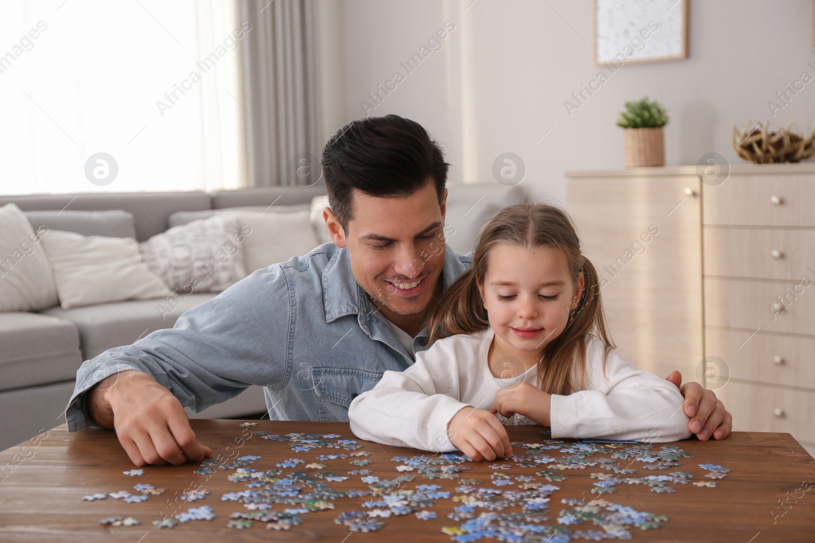 Photo of Man and his little daughter playing with puzzles at home