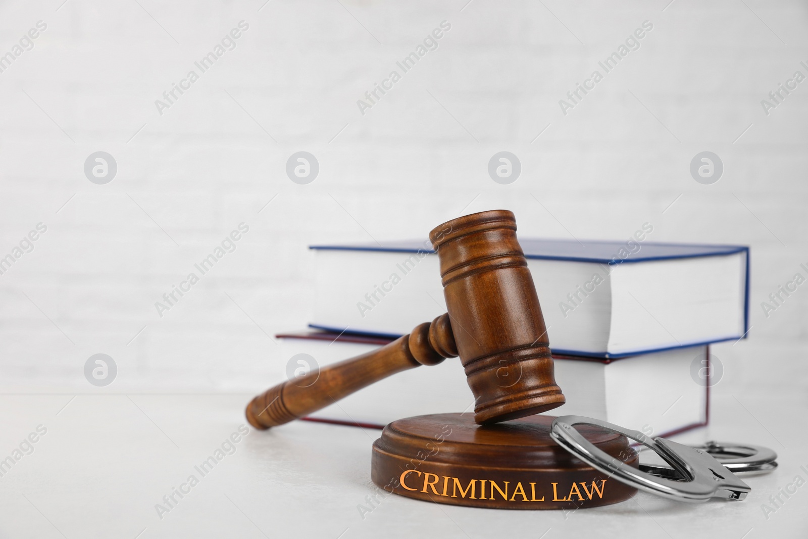 Image of Gavel, handcuffs and books on table against white background. Criminal law concept 