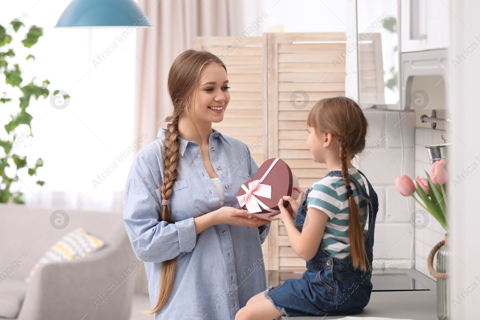 Photo of Happy mother and daughter with gift at home. International Women's Day