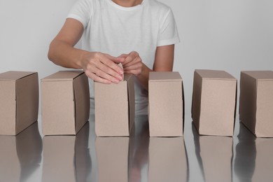 Woman folding cardboard boxes at table, closeup. Production line