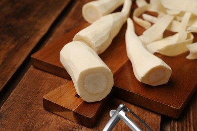 Photo of Whole and cut fresh ripe parsnips on wooden table, closeup