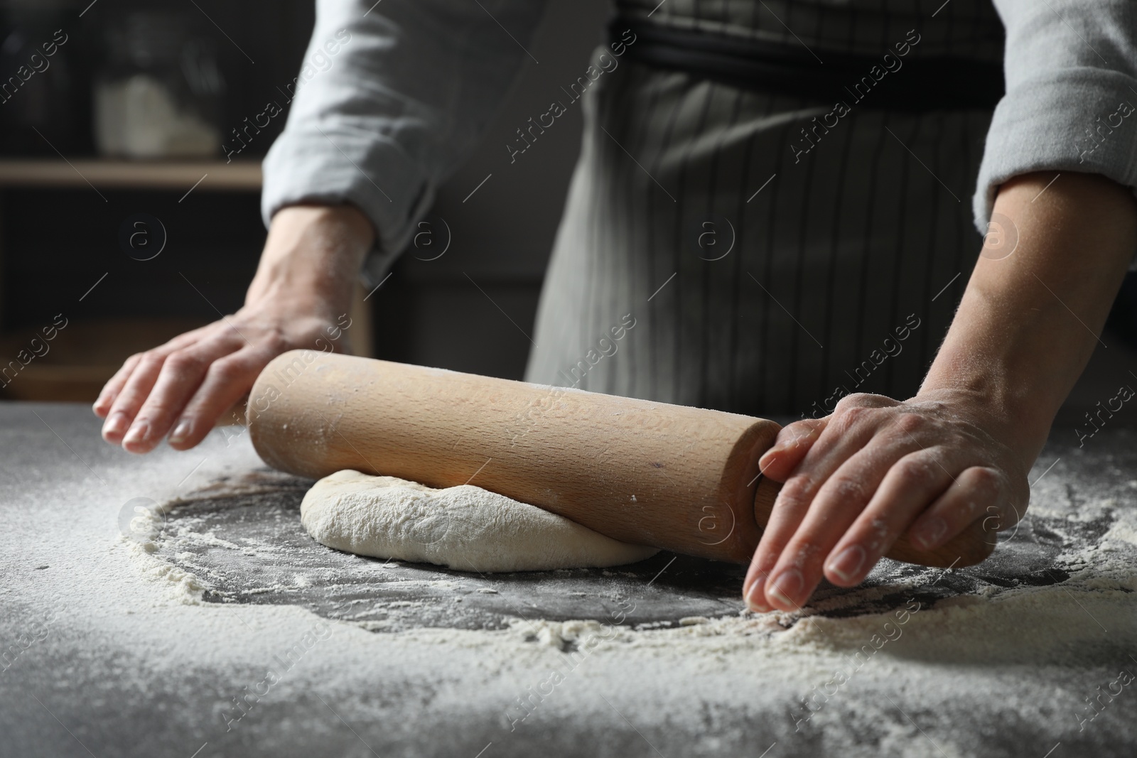 Photo of Woman rolling pizza dough with pin at table, closeup