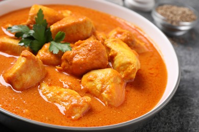 Bowl of delicious chicken curry on grey table, closeup