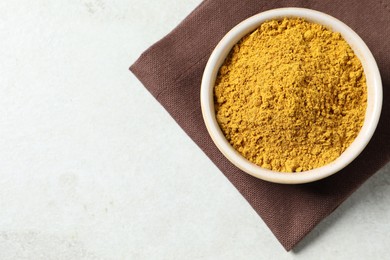 Photo of Curry powder in bowl on white table, top view. Space for text