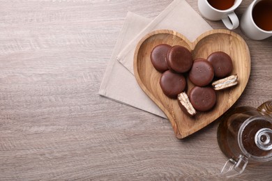 Photo of Tasty choco pies and tea on wooden table, flat lay. Space for text