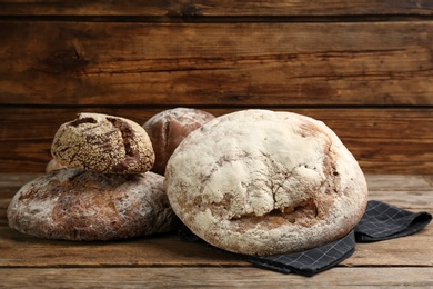 Photo of Different kinds of fresh bread on wooden table