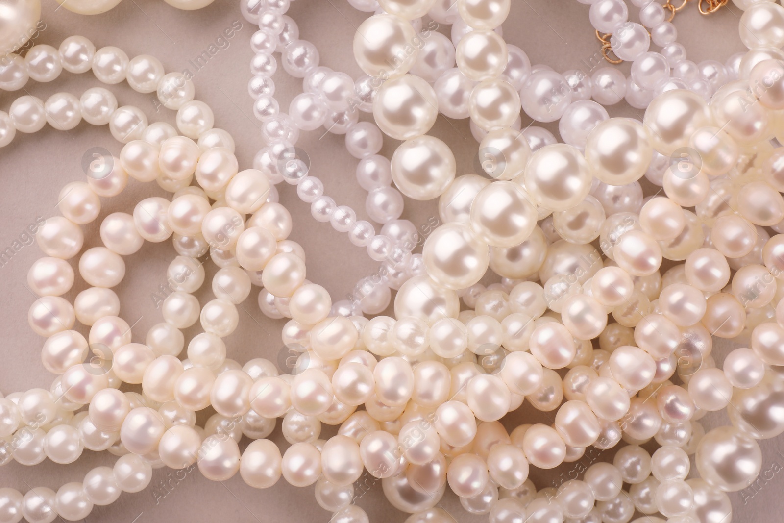 Photo of Elegant pearl necklaces on beige background, top view