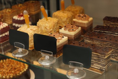 Showcase with different tasty desserts in store, closeup