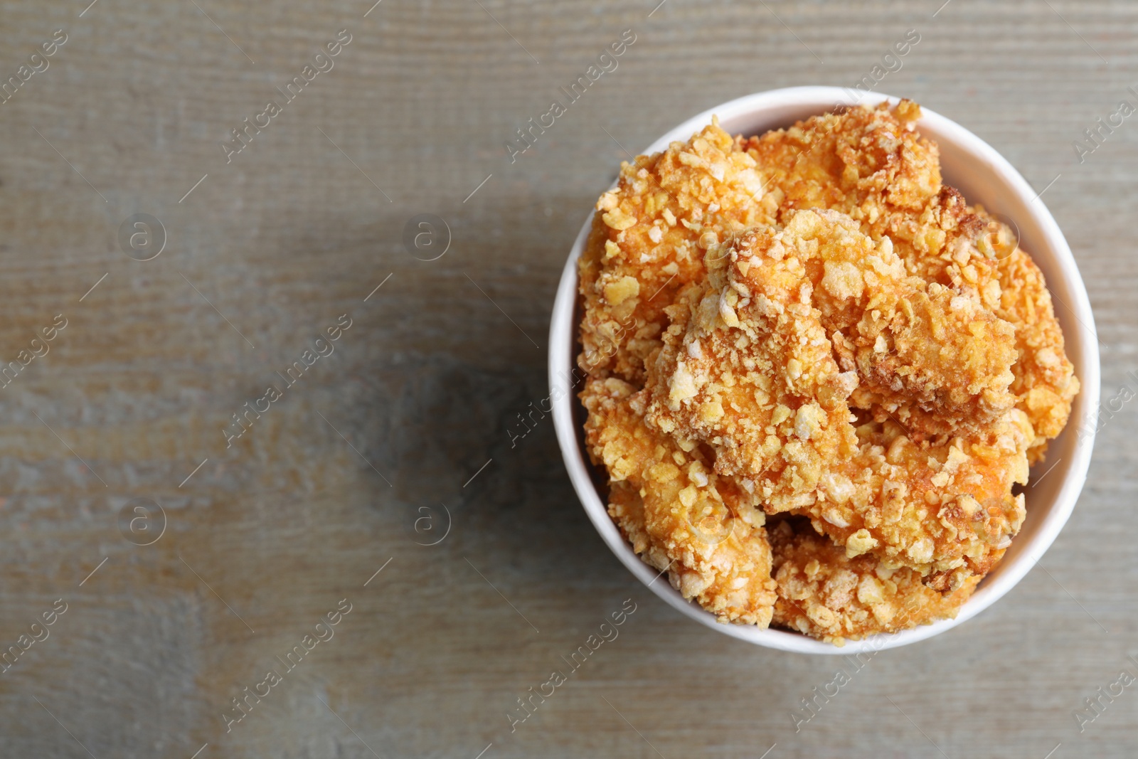 Photo of Bucket with yummy nuggets on wooden table, top view. Space for text